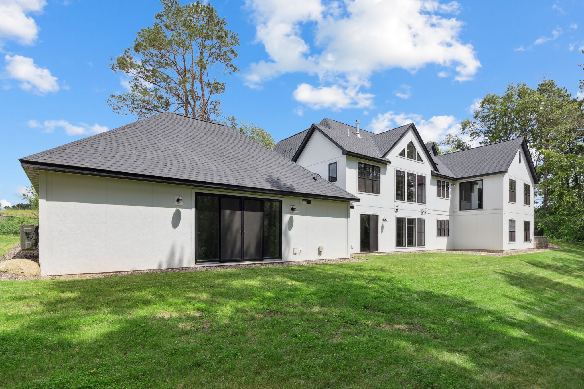 Rear elevation of the home in daylight, showing the full footprint against the wooded lot
