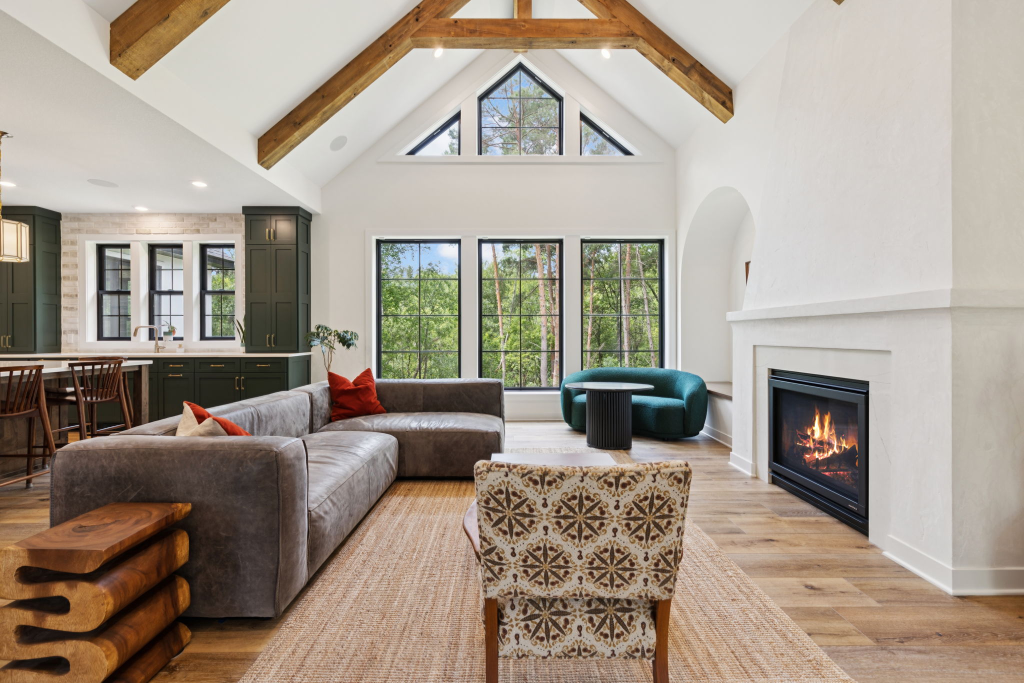 Great room with vaulted timber-beam ceiling, fireplace, and kitchen beyond