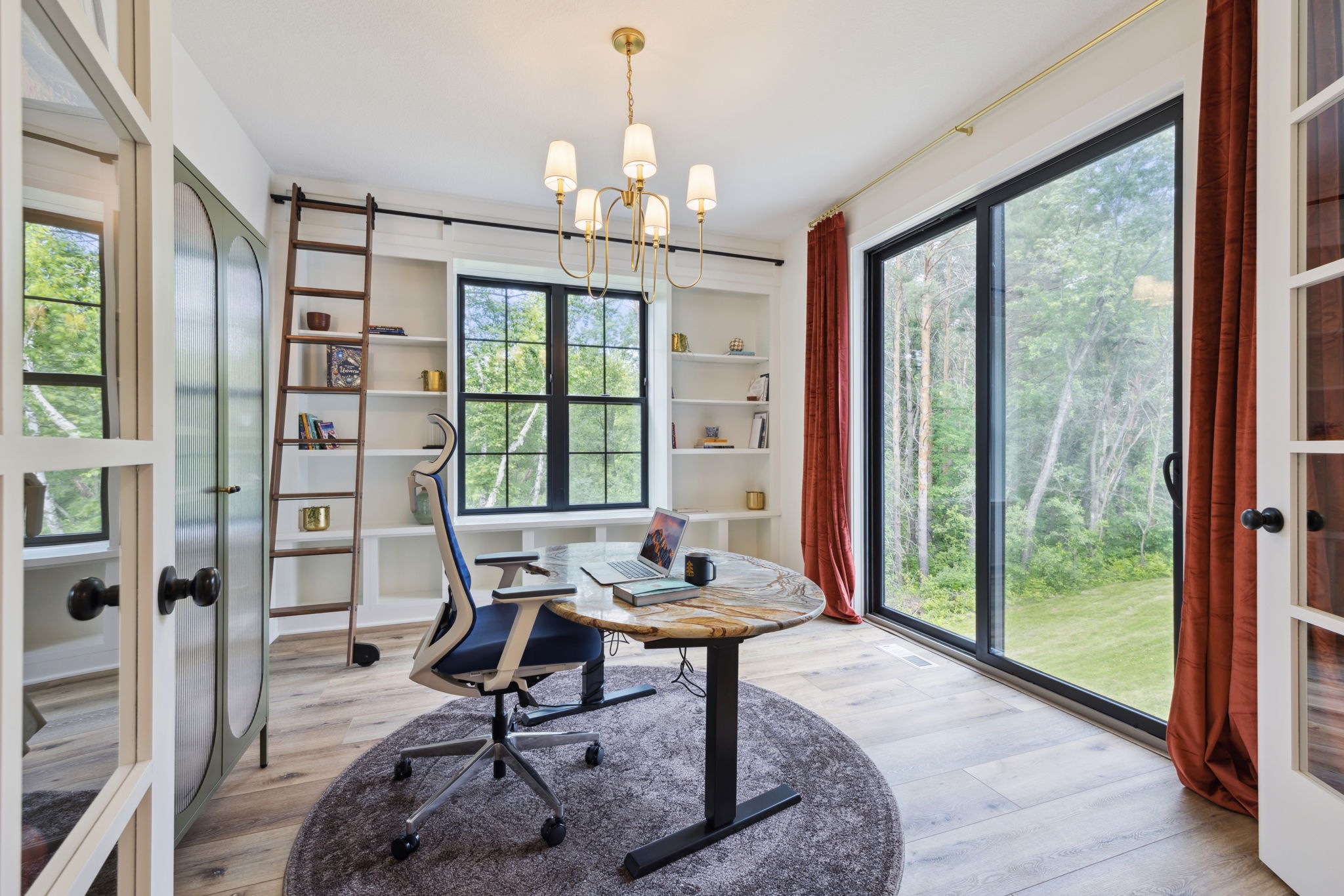 Home office with built-in shelving, library ladder, and picture window