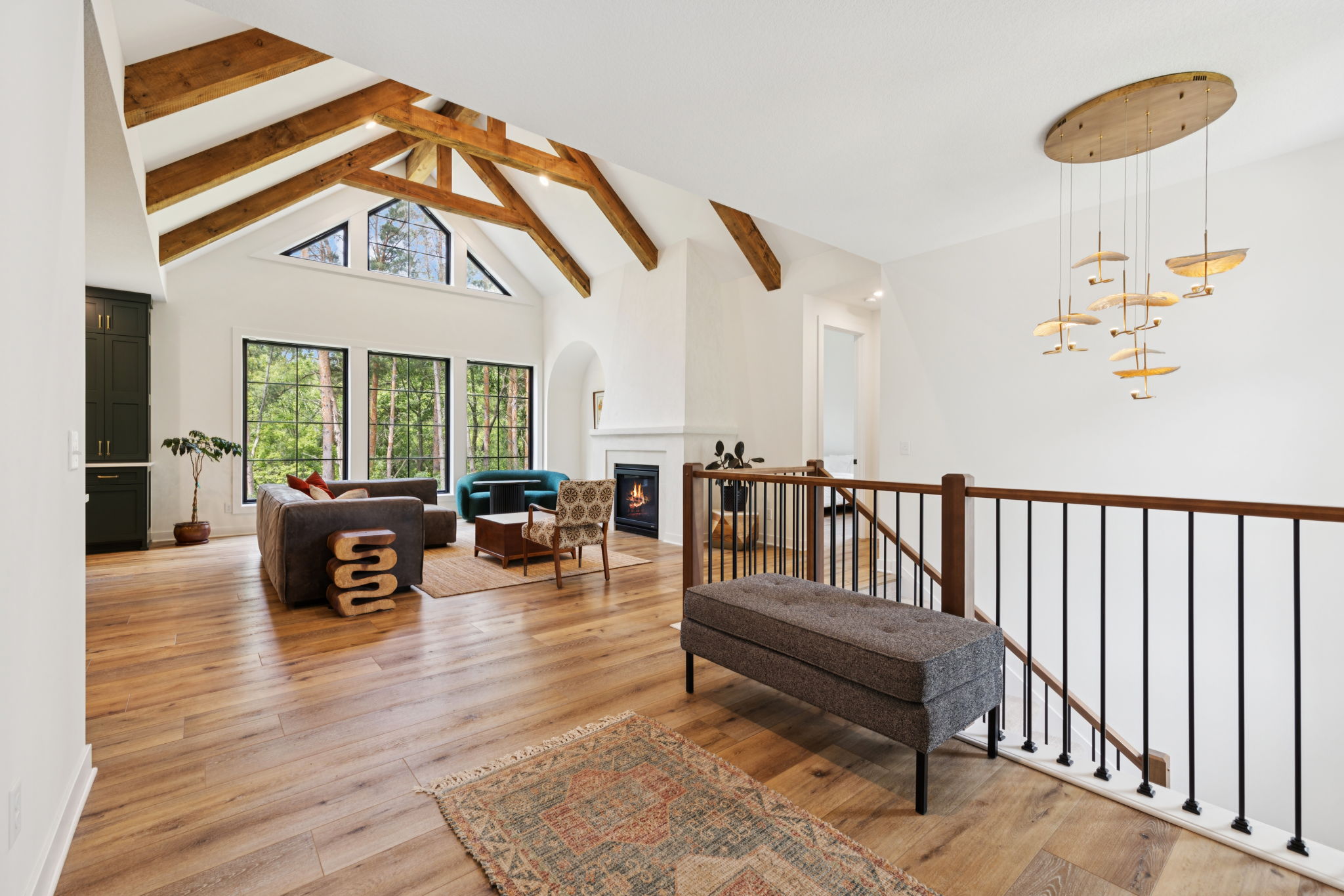 Main-level living room with exposed timber trusses, a fireplace, and the open stairs to the lower level